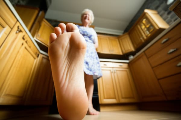 Grandma looks very happy she is from the United States she a american she beautuiful and sweet but really old she got white hair, she has white skined, and she is on a kitchen and putting her feet she have big feet sized 14