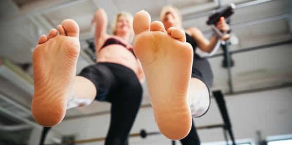 Create an image of two mature 40 year old women,  have their barefeet raised as if to crush/stomp something under their barefeet, a shrink ray gun is in the first woman's hands.  They are both grinning.

